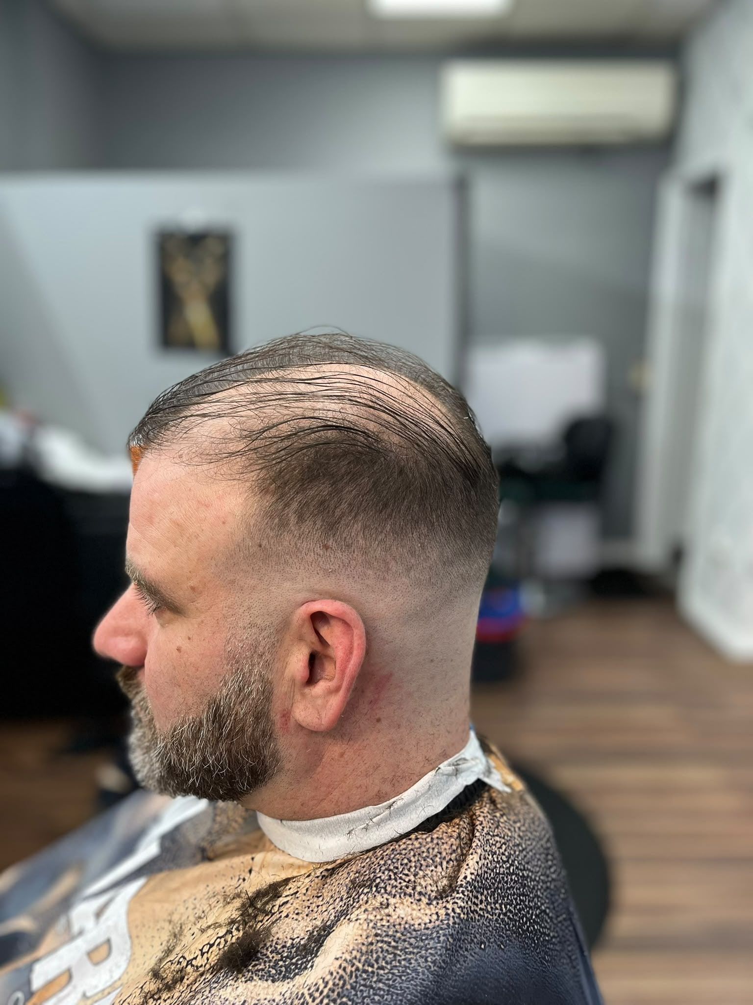 Slick-back with a skin fade and a trimmed full beard